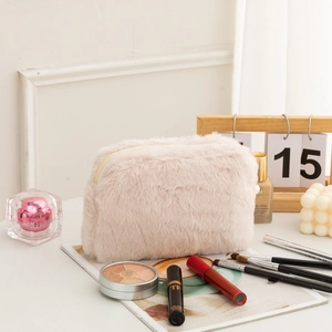 Close-up of soft plush makeup bag in light pink with smooth zipper and faux fur texture