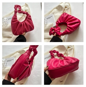 Detail view of fuchsia pleated cloud bag showing glossy PU leather and ruched handle
