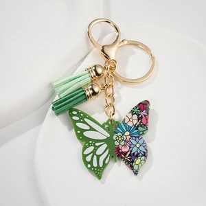 Detail of butterfly keychain with green cutouts, floral patterns and two green tassels