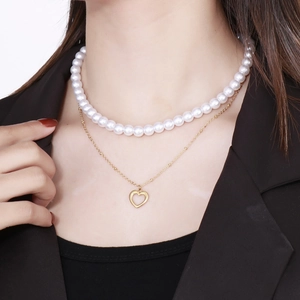 Close-up of double-layer necklace with white faux pearls and golden heart pendant