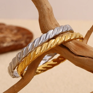 Vue détaillée de bracelets torsadés en or et argent sur un support en bois