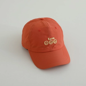 Detail showing the laser-cut ventilation holes and smiley embroidery on the orange cap