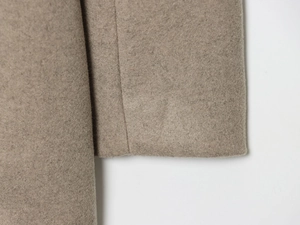 Detailed close-up of wool blend fabric texture and stitching in oatmeal beige color