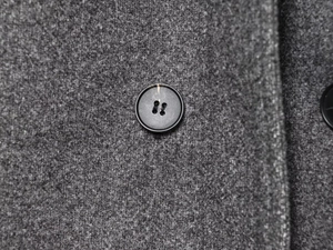 Macro shot of high-quality dark grey wool fabric and matte black four-hole button detail