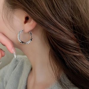 Close-up of silver geometric hoop earrings with zircon accents on female model