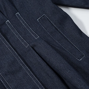 Close-up of white contrast stitching and pocket texture on dark blue denim jacket