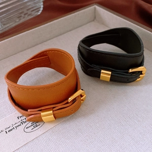 Close-up of wide faux leather chokers in brown and black with gold metal buckles