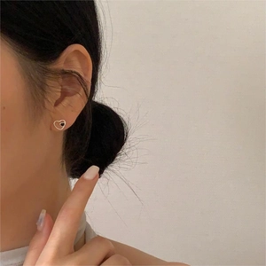 Detail of minimalist 925 sterling silver heart stud earring worn on model earlobe