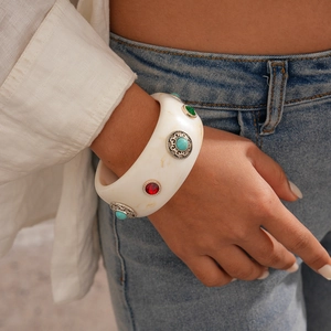 Detail of bohemian acrylic bangle with red and turquoise stones on a female wrist