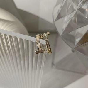 Macro detail of gold T-shape earrings with mother of pearl and sparkling zircon inlay