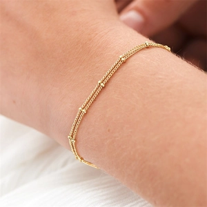 Close-up of a double-layered 14K gold plated bead chain bracelet on a woman wrist