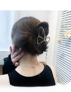 Detail of a gold butterfly hair claw clip with pearl tassels on a woman's hair style