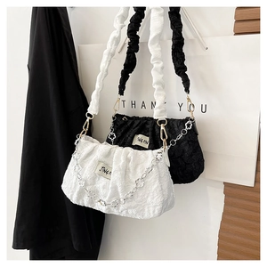 Detail of jacquard fabric texture with ruched strap and flower chain on the cloud bag