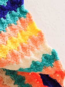 Close-up of colorful crochet knit sweater showing intricate wavy patterns and textures