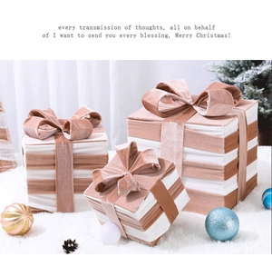 Three-piece white Christmas gift box set with dusty pink velvet ribbons on plush carpet
