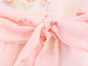 Détail de robe en mousseline rose à fleurs avec nœud élégant et bouton perle