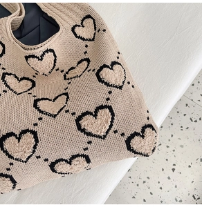 Gros plan d'un sac cabas en maille beige avec motifs de cœurs noirs et texture en peluche