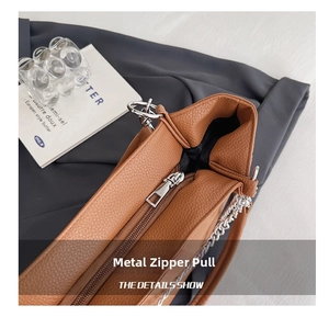 Detail of silver zipper and brown lychee grain leather texture on large tote bag