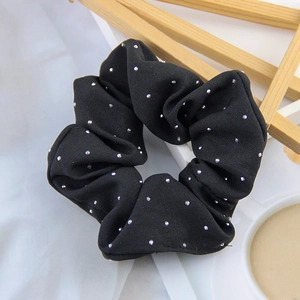 Detailed view of a black elastic hair scrunchie with sparkling silver polka dots texture