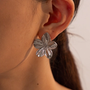 Elegant silver flower stud earrings with brushed metal texture worn by a model