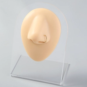 Close-up of a minimalist golden U-shaped stainless steel nose ring on a nose model