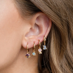 Gold star and planet earrings set with colorful zircons on female ear lobe