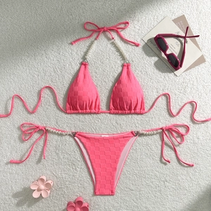 Detailed view of pink checkerboard bikini with pearl straps and decorative summer accessories