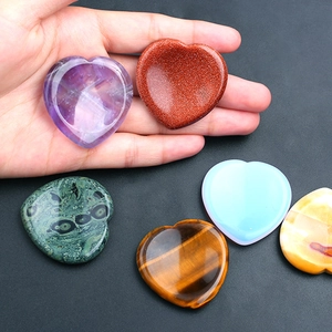 Polished heart-shaped natural crystals in various gemstones held for size comparison