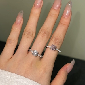 Close-up of square cut white and pink zircon stones on silver rings worn by hand