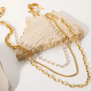 Three-layer 18K gold plated stainless steel necklace with faux pearls on stone pedestal