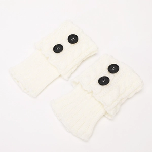 Detail of white cable knit boot cuffs featuring two black buttons and thick wool texture