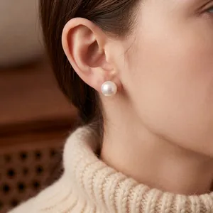 French style minimalist round pearl stud earring worn on model with knit sweater background