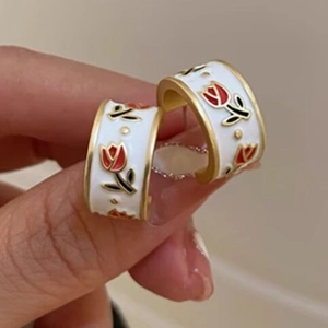 Close-up of vintage French tulip earrings with white enamel and golden C-shaped design