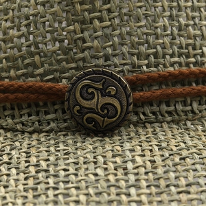 Detailed close-up of straw woven texture with vintage brass emblem on cowboy hat
