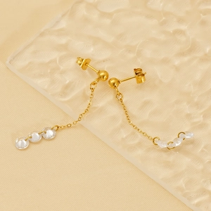 Elegant gold tassel earrings with clear crystals on a warm textured backdrop