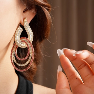 Close-up of gold geometric drop earrings with pink zircons worn by a model