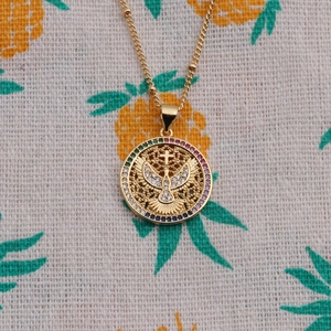 Collier pendentif colombe et croix dorée avec zircons colorés sur tissu à motifs