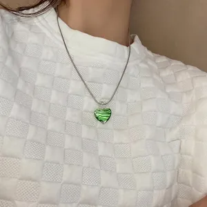 Close-up of green heart pendant with zebra patterns on a silver chain necklace