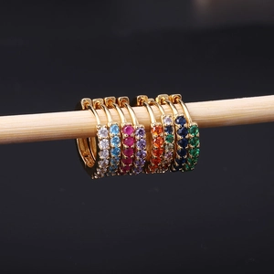 Detail of colorful cubic zirconia stones set in gold-plated huggie hoop earrings