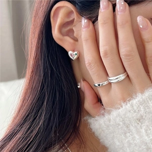Detailed shot of S925 sterling silver heart earrings and stacked geometric rings on a model