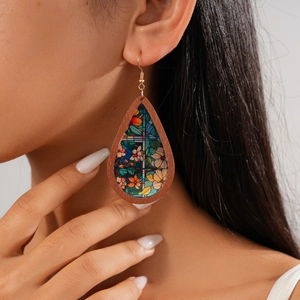 Detailed view of bohemian teardrop wood earrings with floral acrylic print on a model