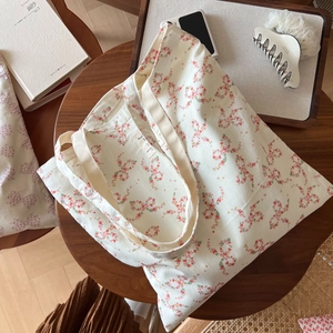 Sac cabas en coton à fleurs avec nœud rose sur une table en bois avec accessoires
