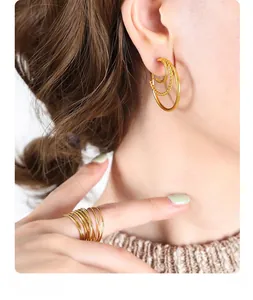 Macro view of tiered C-shaped golden earrings with twisted texture and stacked rings