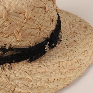 Détail du chapeau de paille avec dentelle florale noire et pendentif éclair argenté