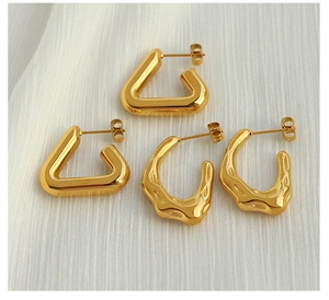 Detail showing gold triangle earrings and lava textured hoops on white fabric