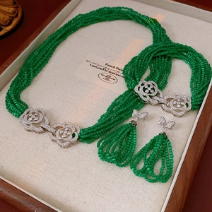Detailed set of floral bead necklace, bracelet, and earrings on a linen display tray