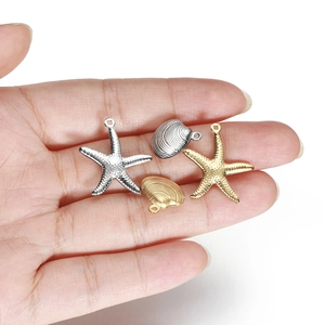 18k gold and silver starfish and shell pendants held in hand for jewelry DIY