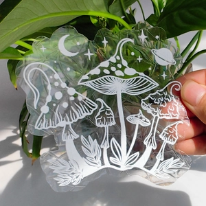 Detail of a transparent suncatcher sticker with white mushroom and celestial patterns