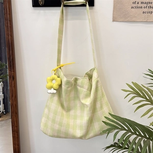 Detail of green and white plaid canvas tote bag with adjustable strap and flower charm