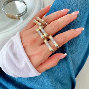 Luxurious stackable gold and silver pavé diamond tube rings worn on fingers